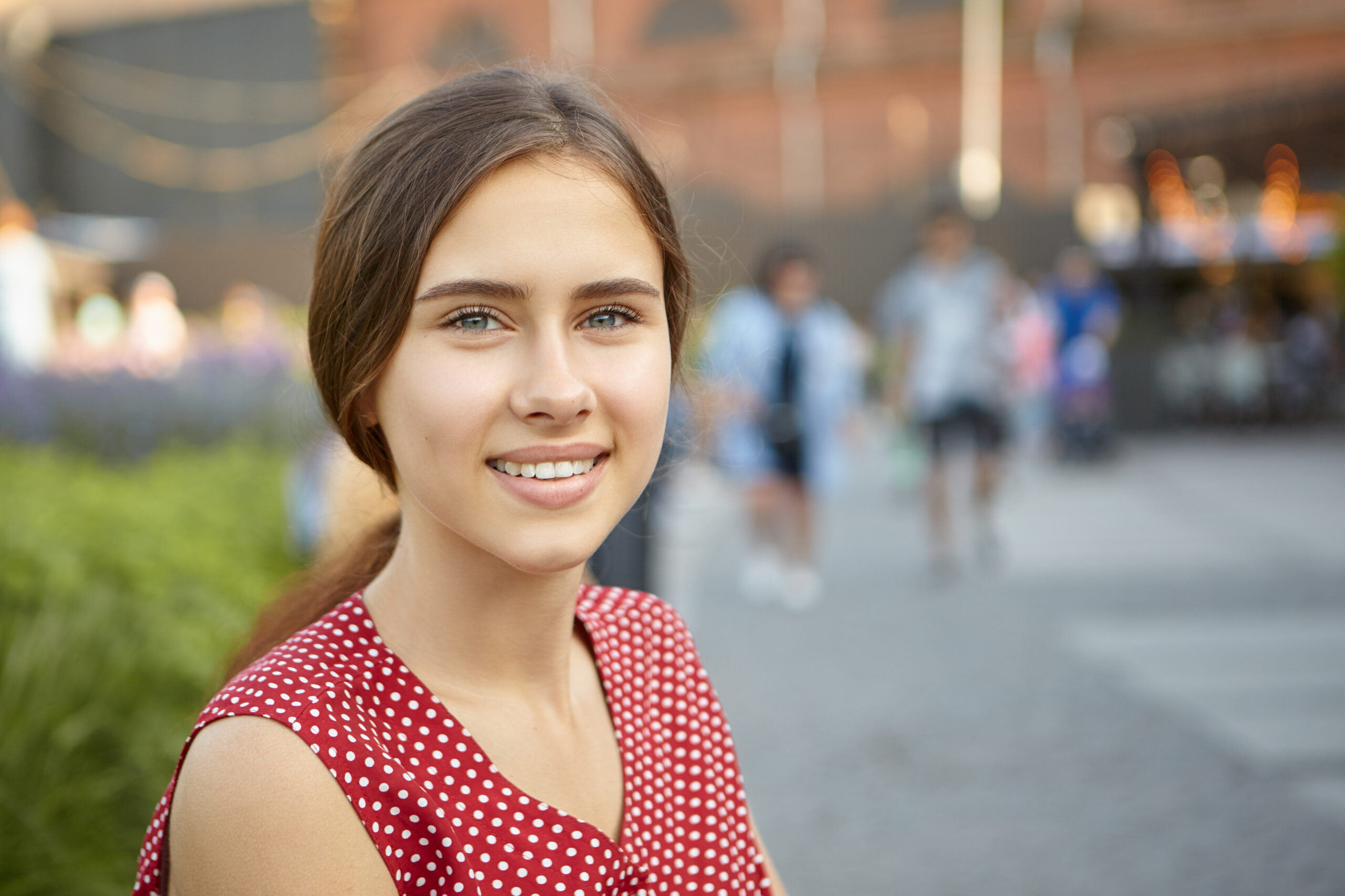 close up image charming gorgeous young woman with perfect tanned skin straight teeth hair gathered ponytail with positive beautiful smile posing outdoors park scaled